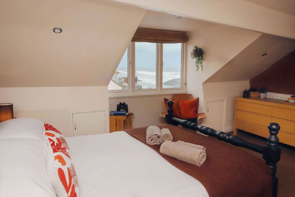 An inviting bedroom with a bed, TV, dresser, and window.