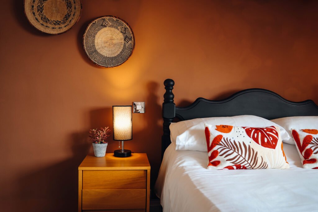 A cosy bedroom with lamp on a bedside table.