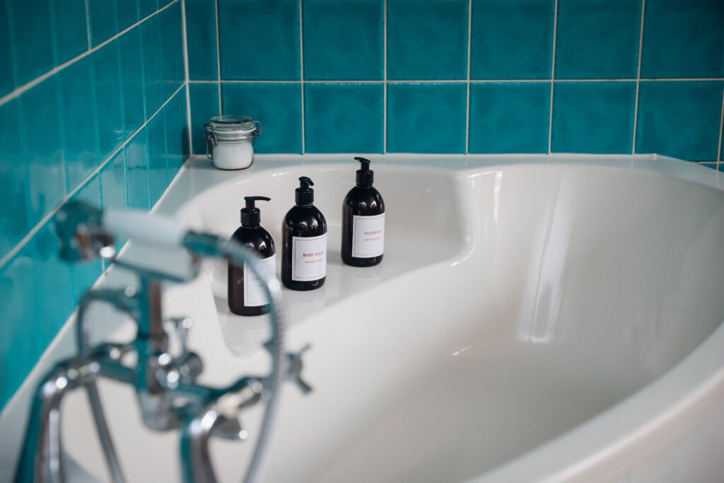 Soap bottles nearly lined up on a bath.