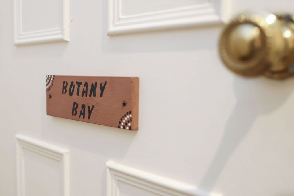A white door with a wooden sign reading ' Botany Bay'.
