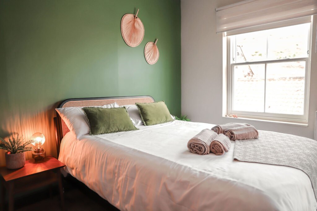 White bed with green pillows.