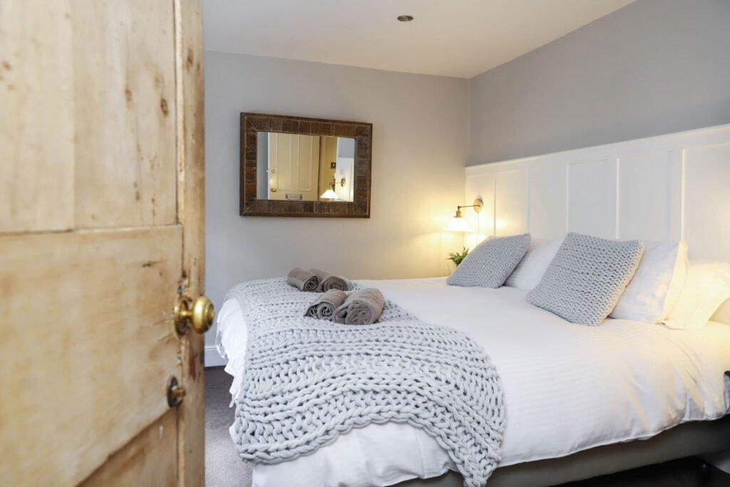 A cozy bedroom with a neatly made bed and a large mirror on the wall.