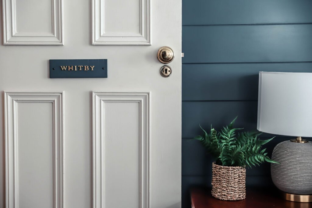 A white door with a dark blue sign which reads 'Whitby'.