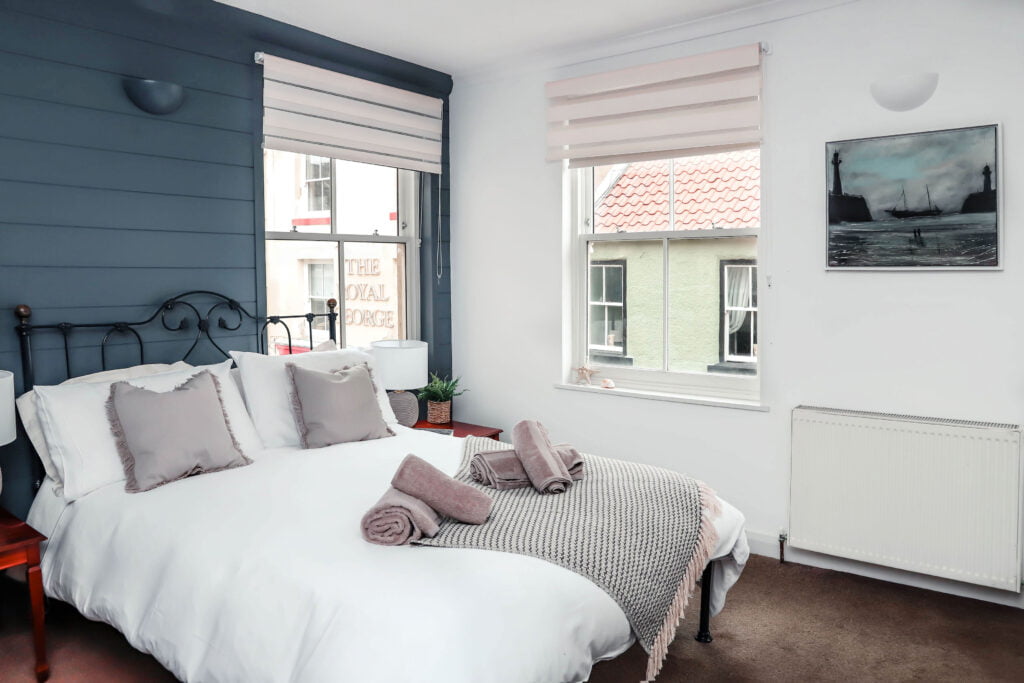 A light and cosy bedroom with neatly folded towels resting on the bed.