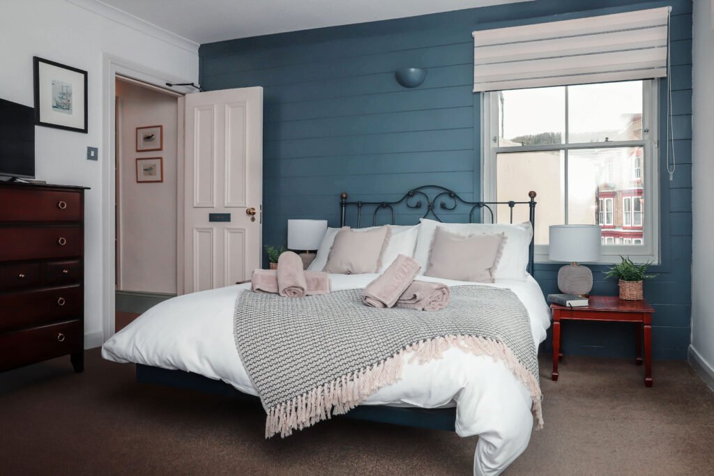 A cozy bedroom with bed, TV and blue panelled walls.