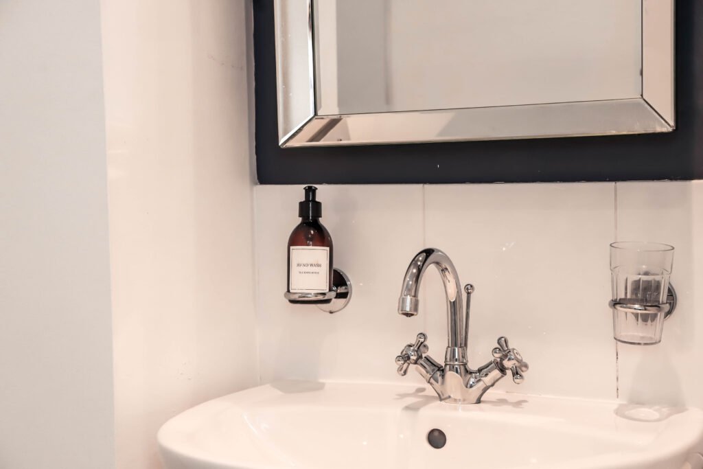 A sink with a silver tap accompanied by bottle hand wash.